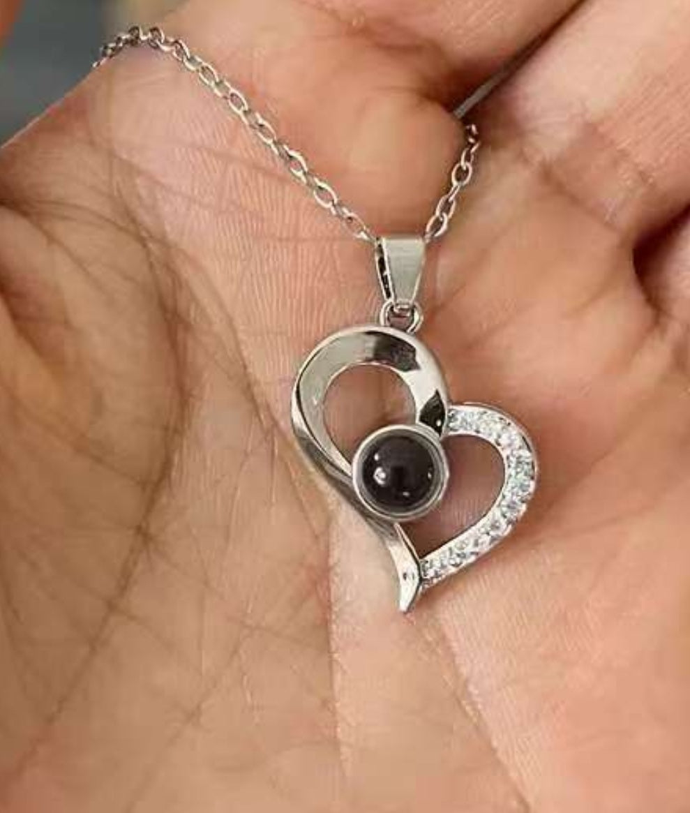 Close-up of the I Love You projection necklace pendant — light projects '100 Languages' message