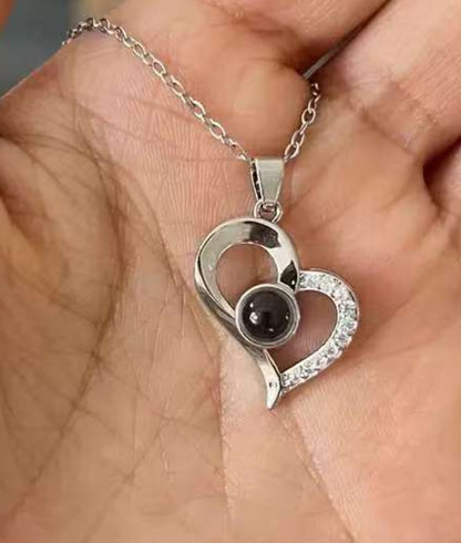 Close-up of the I Love You projection necklace pendant — light projects '100 Languages' message